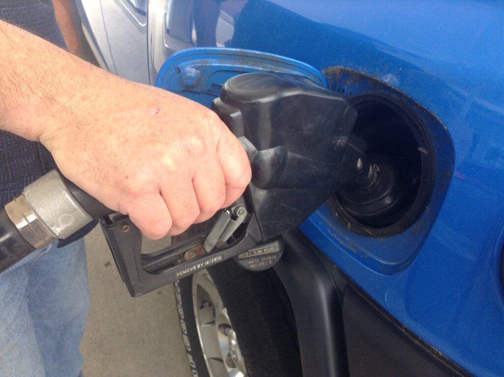 Close-up of a hand holding a gas pump nozzle in a car's fuel tank