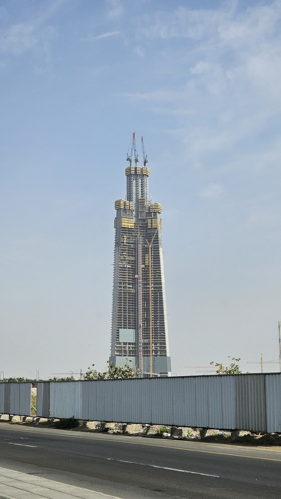 Jeddah Tower construction with cranes at the top, seen from street level in Jeddah
