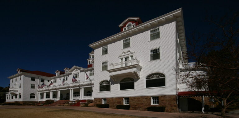The main building of the Stanley Hotel in Estes Park, Colorado, a white Colonial Revival hotel against a blue sky