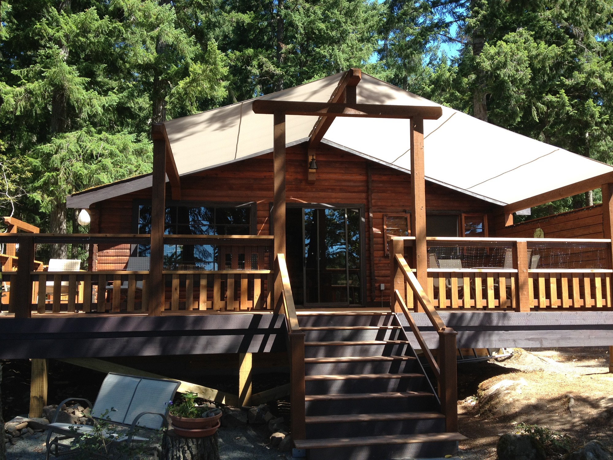 Wooden vacation rental cabin with a covered porch, surrounded by trees